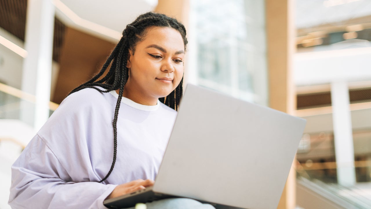 Young Black woman using a silver laptop.