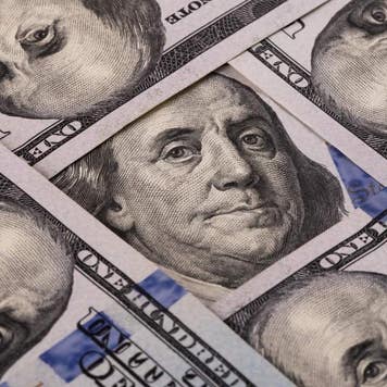 Fragments of five $100 bills showing Benjamin Franklin's face five times in a diamond shape.