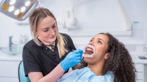 A dentist works in the open mouth of a patient