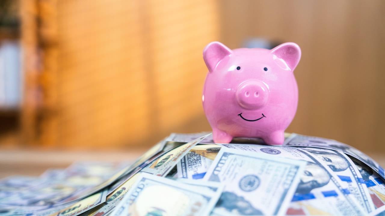 piggy bank on top of pile of cash