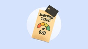 Image of a credit card lying on top of a stylized credit score card that has Subprime Credit at the top of the score card and 620 at the bottom with a colored gauge (sections in red, orange, yellow, and green) in the middle. The indicator is pointing just in the green section.