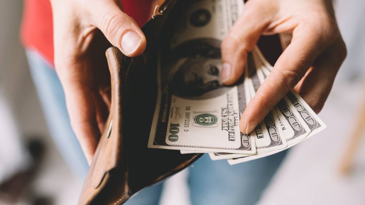 person opening wallet with cash inside