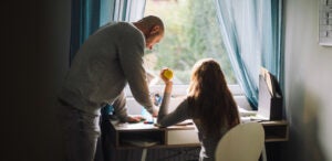 A bald man helps his teenage daughter with homework