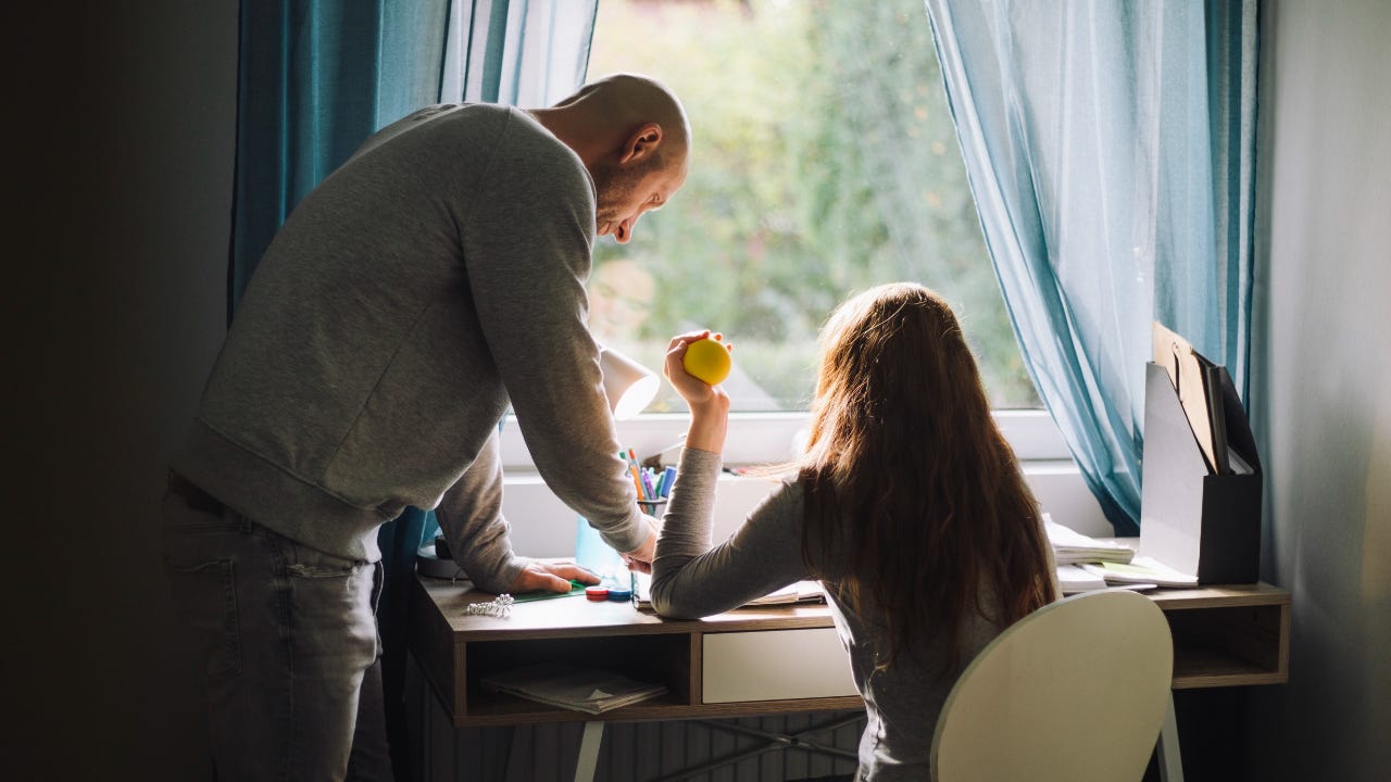 A bald man helps his teenage daughter with homework