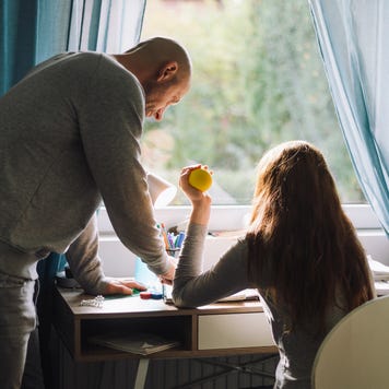 A bald man helps his teenage daughter with homework