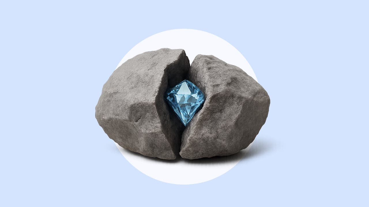 A diamond sits inside of a split rock on a blue background.