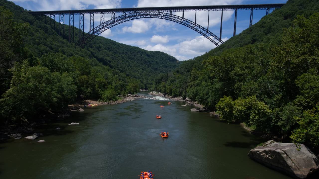 A large bridge over a body of water with boaters.
