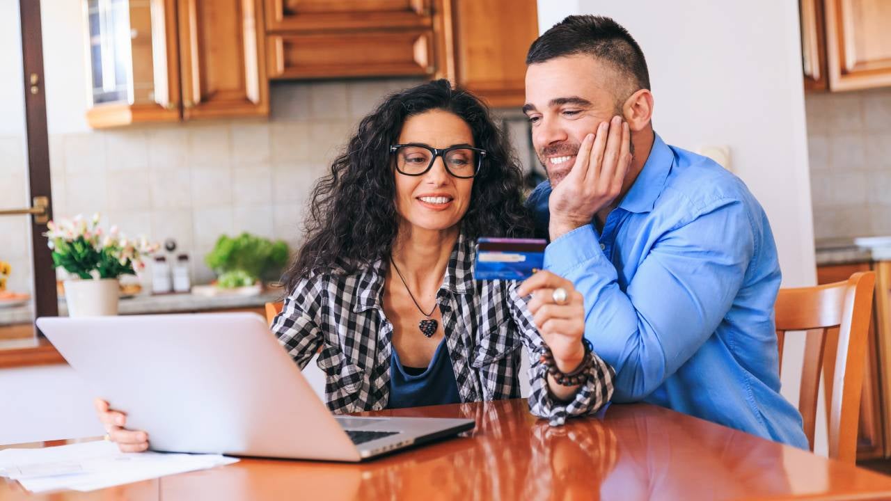 Happy couple using credit card and laptop at home