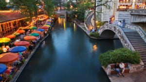 A couple sit along the San Antonio, Texas, river walk at sunset.