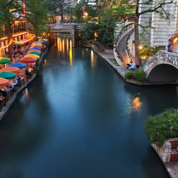 A couple sit along the San Antonio, Texas, river walk at sunset.