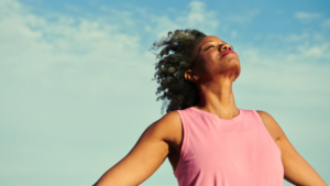 Woman standing on a windy beach with the sky in the background.