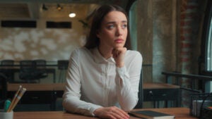 Young woman sitting at table looking thoughtful.