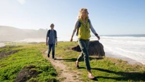 A couple walking on a path on the California coast.