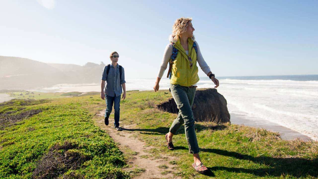 A couple walking on a path on the California coast.