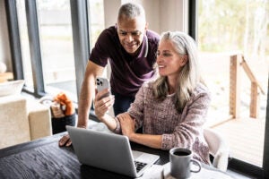 Couple looking at a laptop and a smartphone.