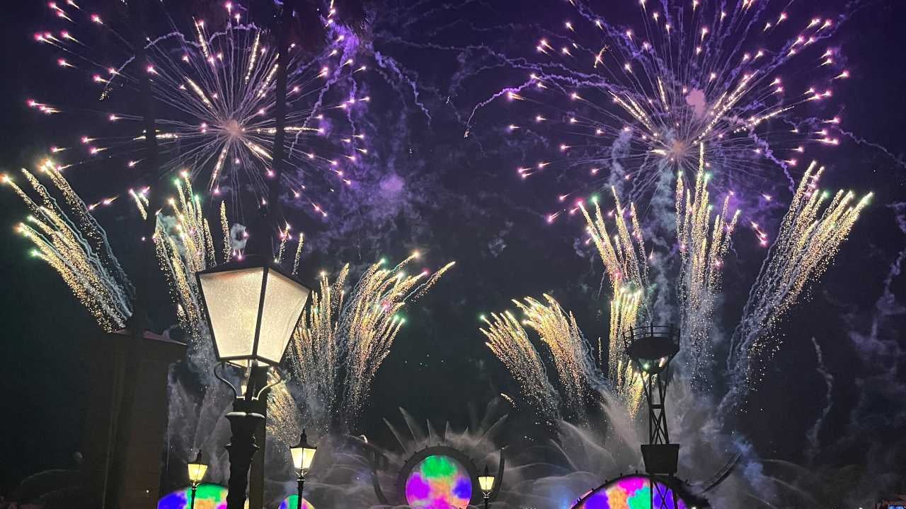 Picture taken at Disney at night, pointing up toward the sky with fireworks in the background.