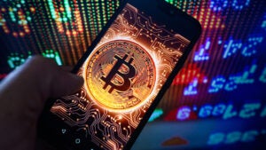 A conceptual coin with Bitcoin's logo is shown on a smartphone screen.