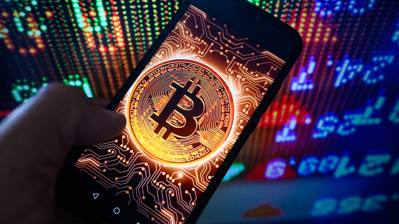 A conceptual coin with Bitcoin's logo is shown on a smartphone screen.