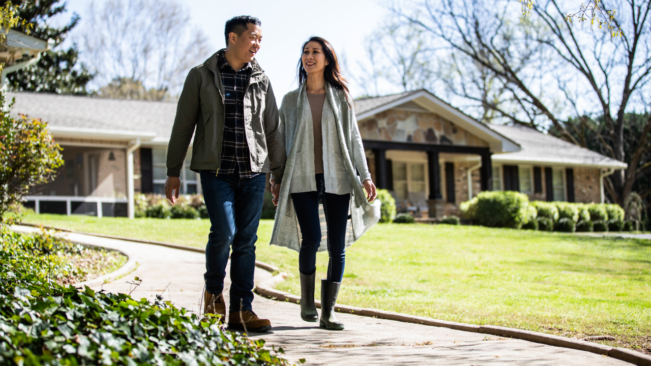 Couple walking in front of a home.