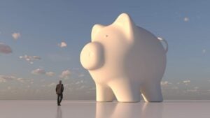 Computer artwork of a businessman looking at giant, white piggy bank.