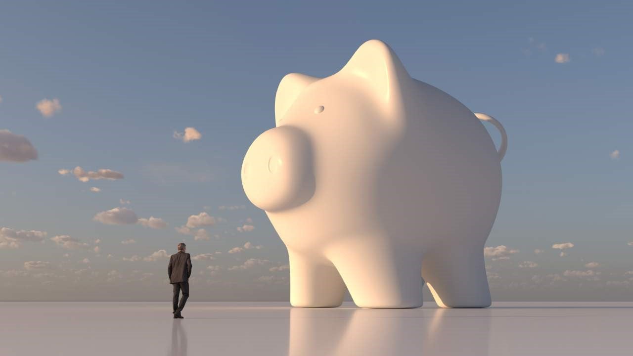 Computer artwork of a businessman looking at giant, white piggy bank.