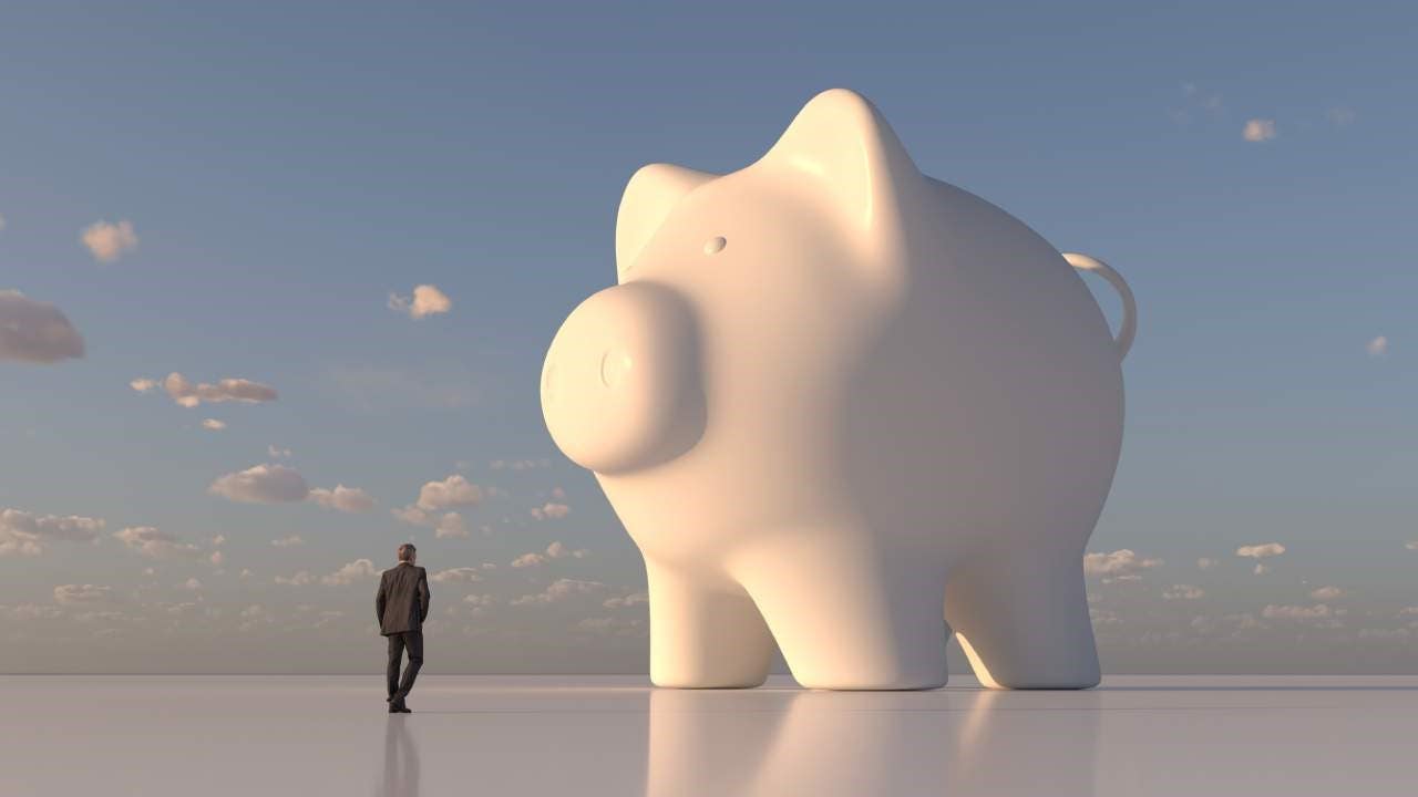 Computer artwork of a businessman looking at giant, white piggy bank.