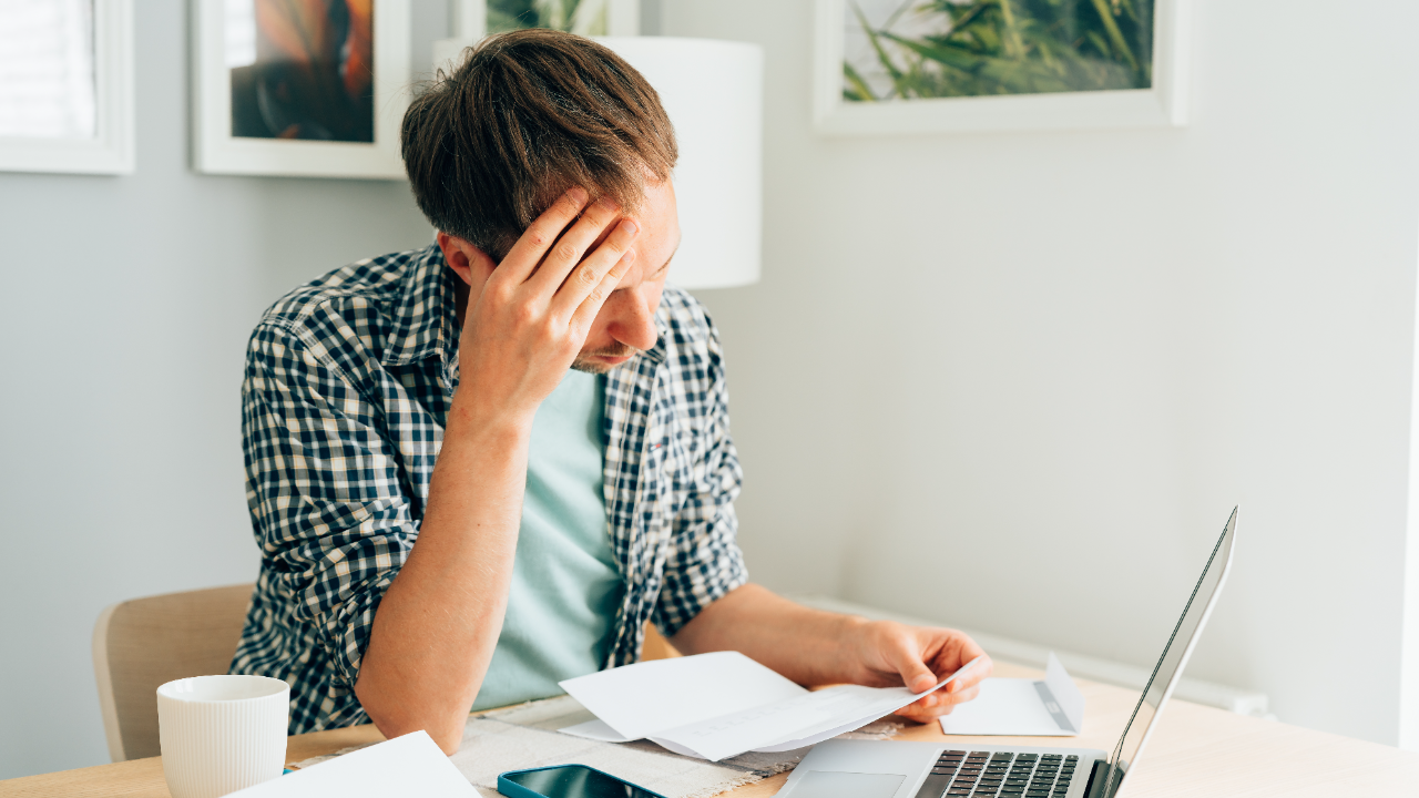 A man looks pensively at a bill he received