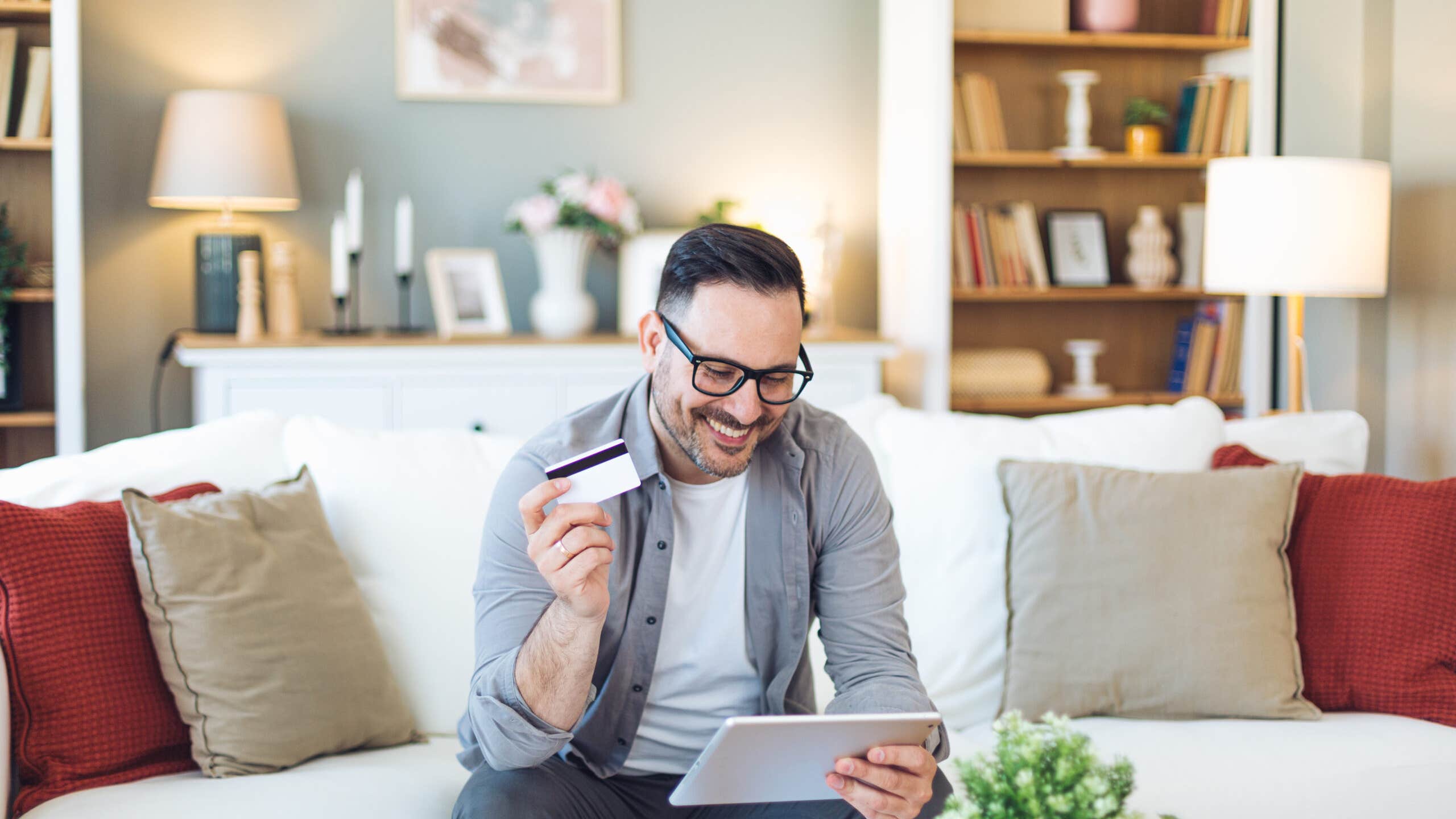 Smiling man holds tablet and credit card.