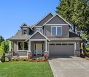 exterior of tidy gray suburban house with green lawn and blue sky