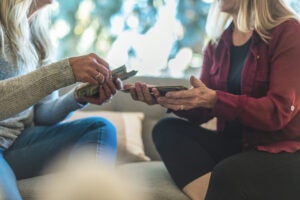 Two women exchanging money on a couch.