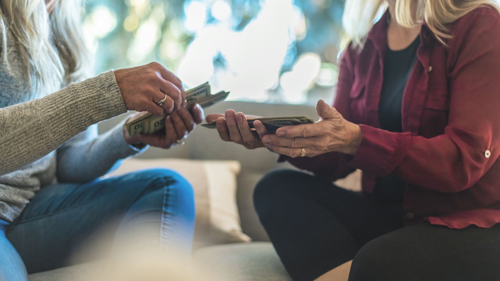 Two women exchanging money on a couch.