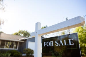 A closeup of a For Sale sign in front of a home.
