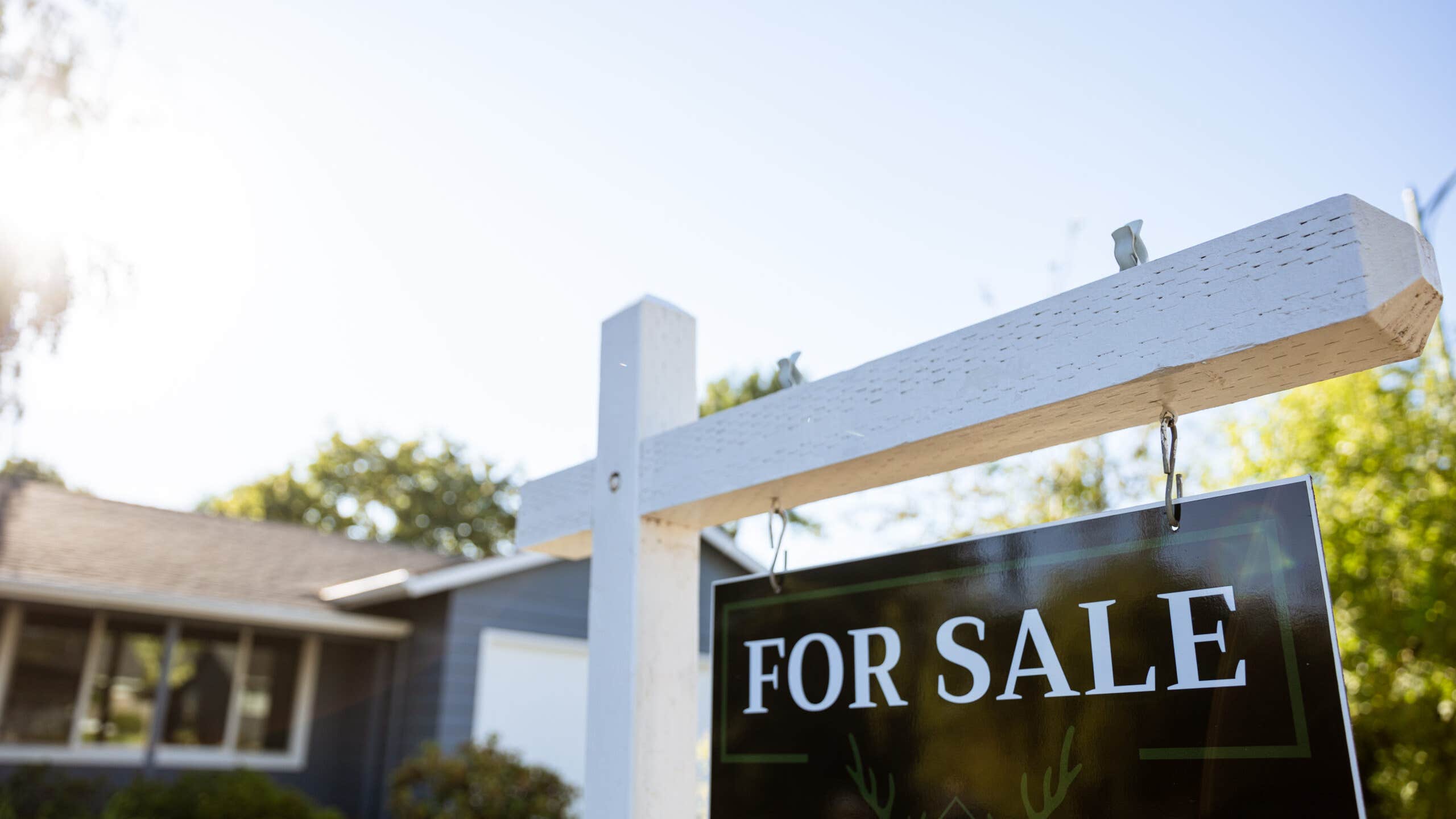 A closeup of a For Sale sign in front of a home.