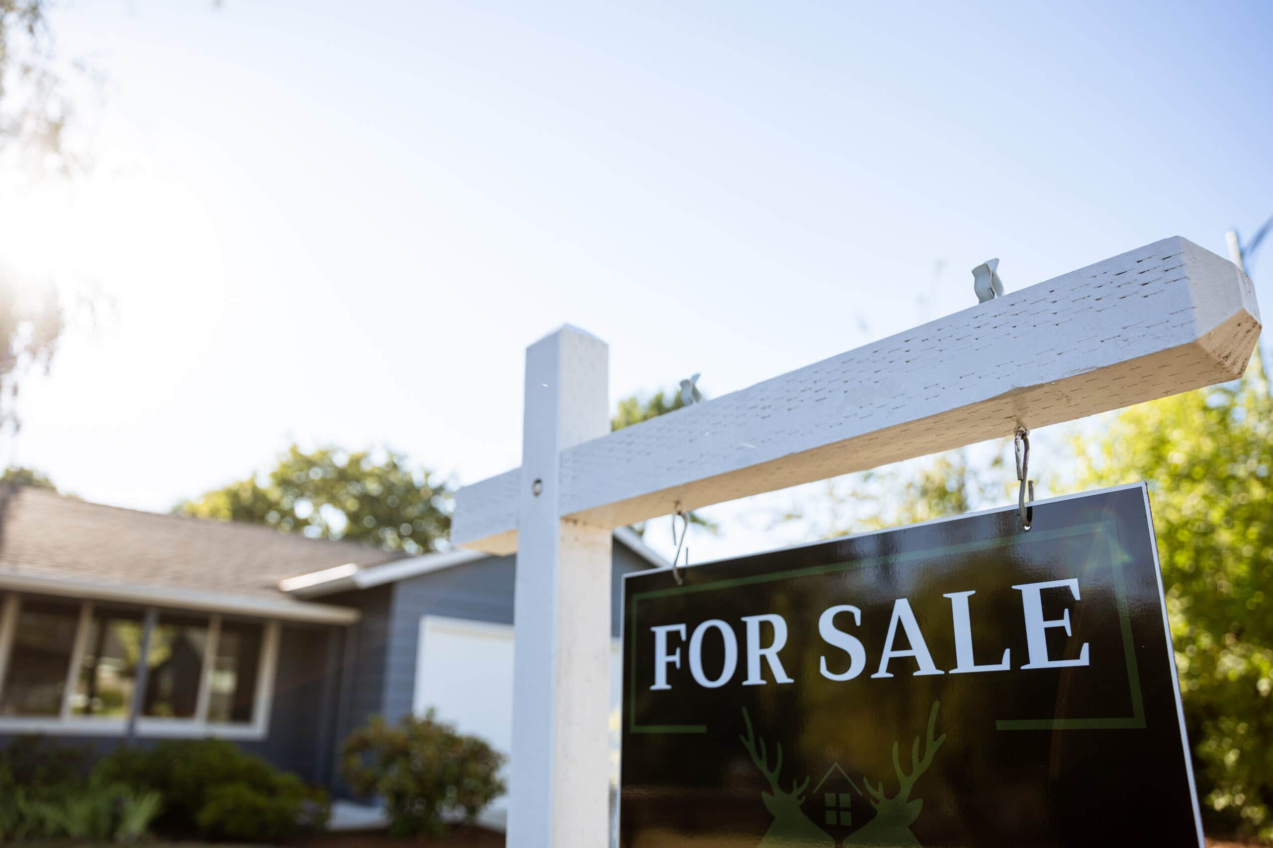 A closeup of a For Sale sign in front of a home.