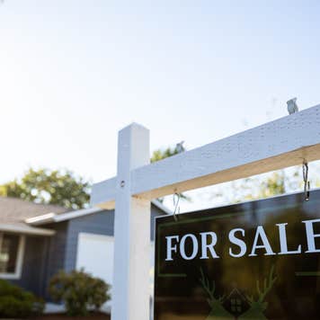 A closeup of a For Sale sign in front of a home.