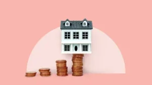 house balanced on stack of coins, pink background, photo illustration