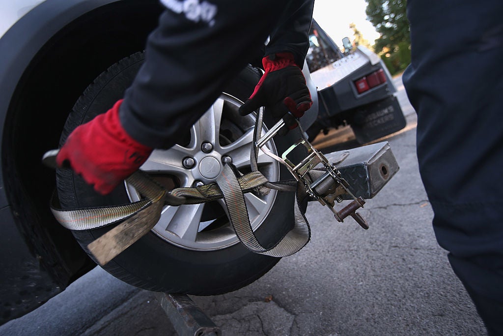 Recovery agent or 'repo man' Jeff Grevelding secures a car for towing while repossessing cars on October 11, 2012 in Syracuse, New York. Grevelding, who works for Advanced Recovery of New York, works with fellow agents day and night locating and towing vehicles legally repossessed by banks and loan agencies, after the owners stop making payments.