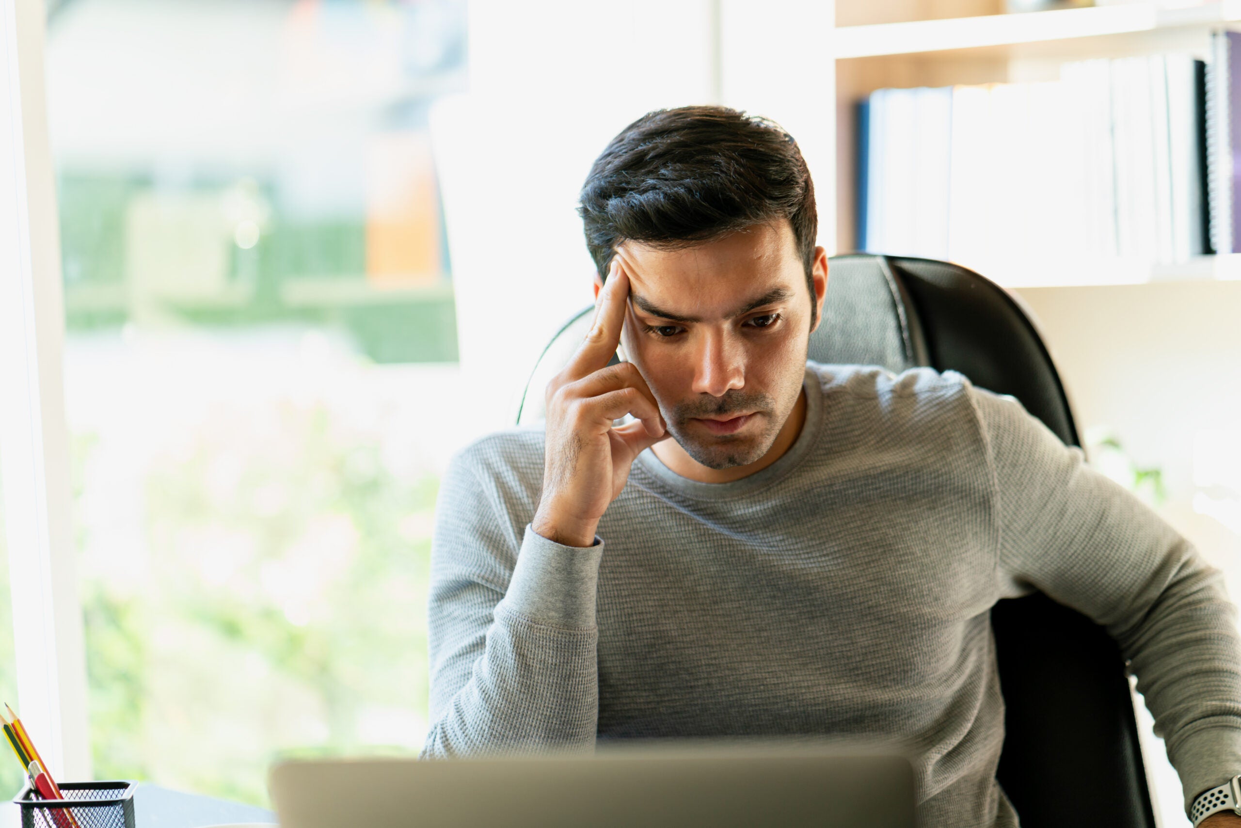 Man looking confused while staring at a laptop screen