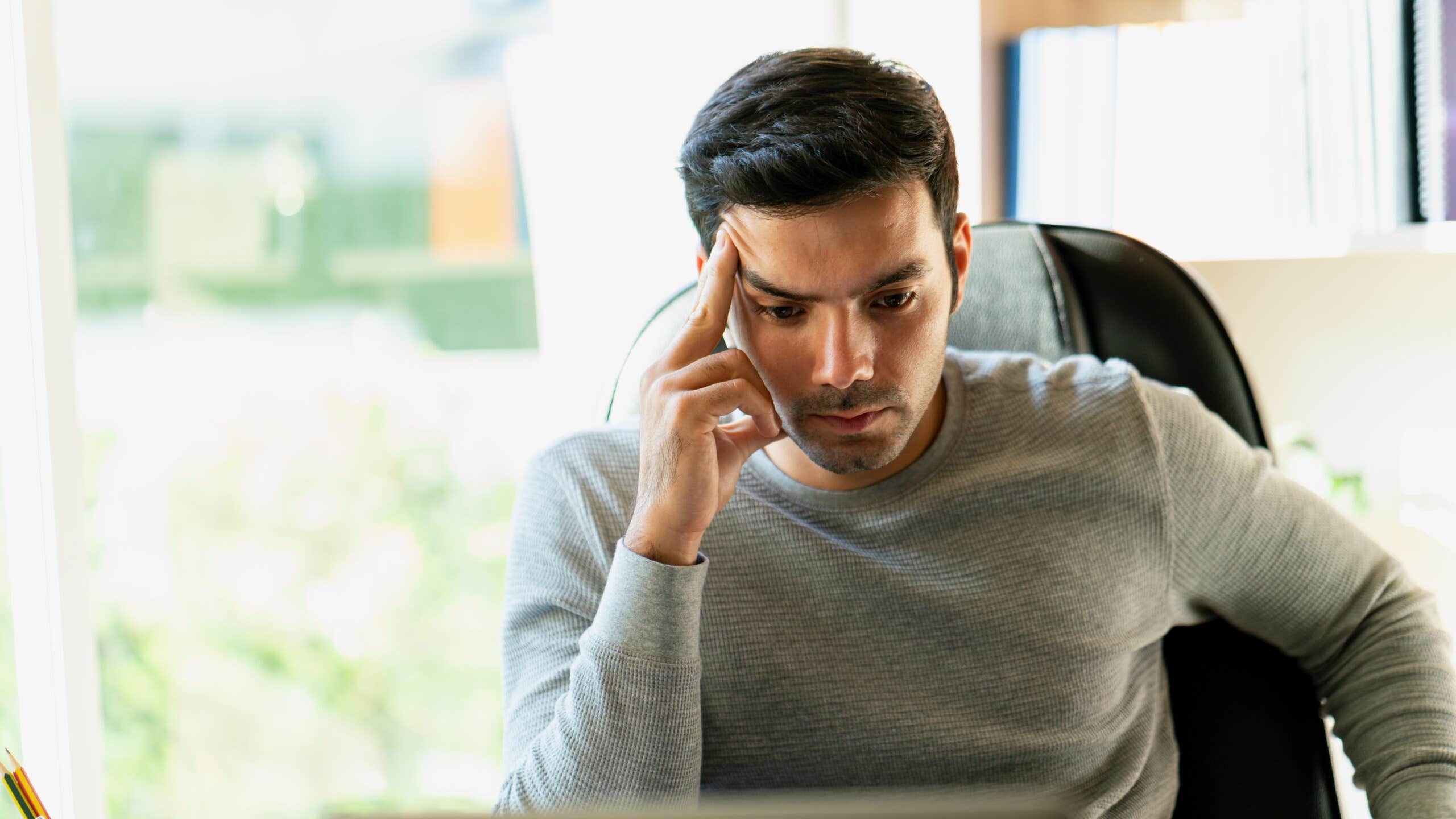 Man looking confused while staring at a laptop screen