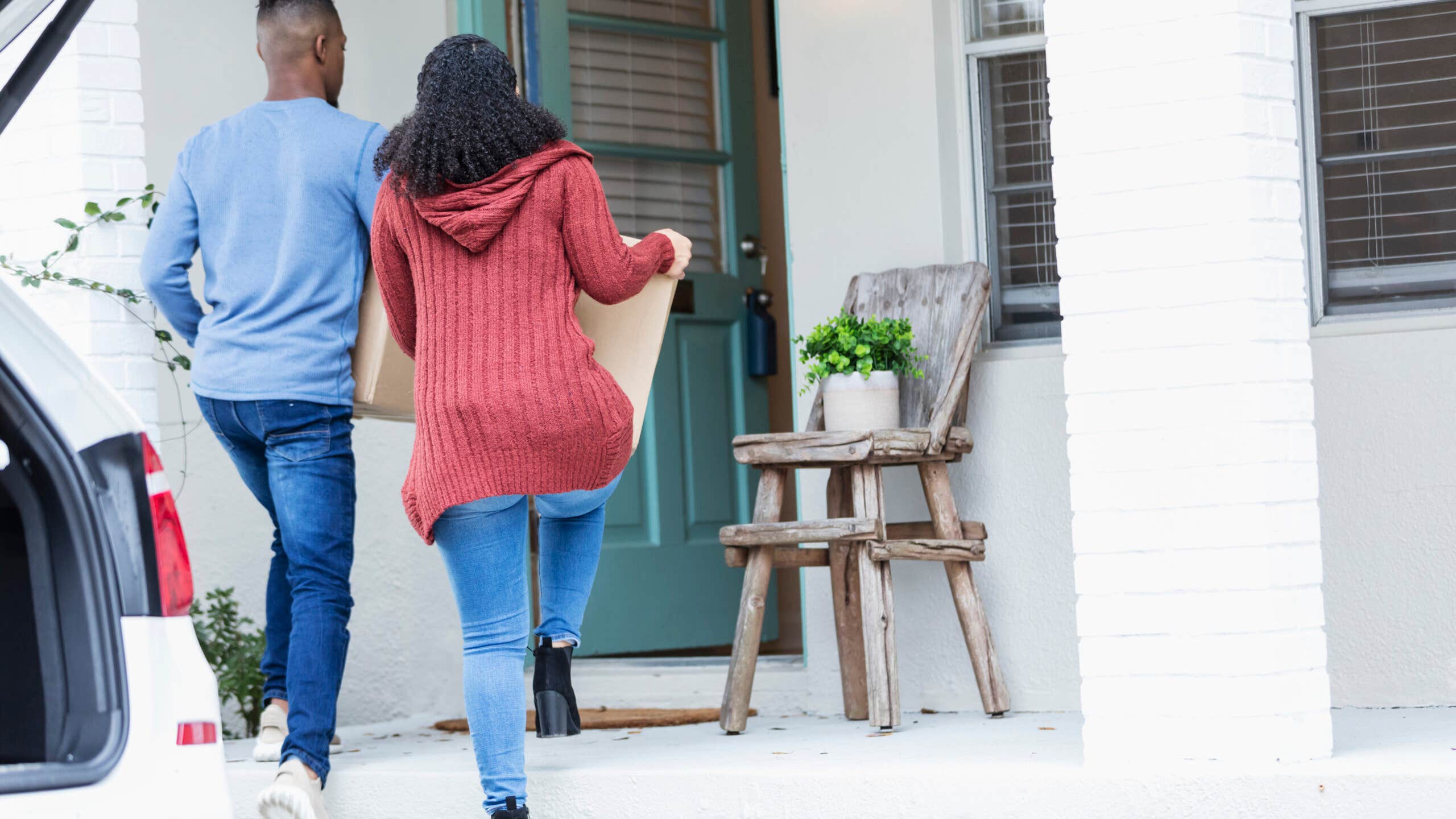 Young couple walks into a new home carrying boxes