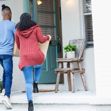 Young couple walks into a new home carrying boxes