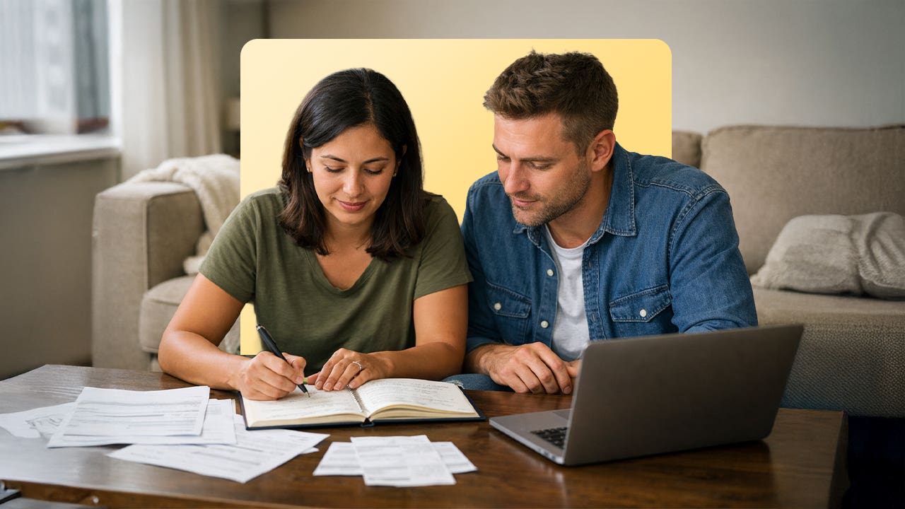 A man and woman sit close together and look at books and a computer.