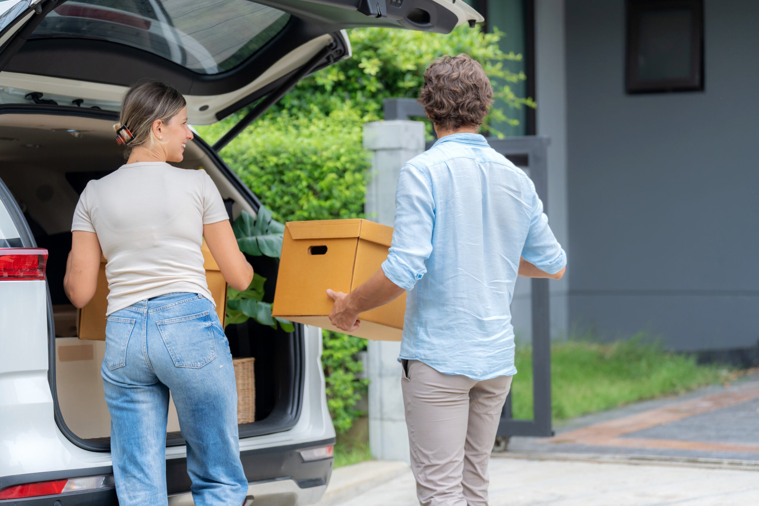 Young couple unloads boxes from the back of a vehicle.