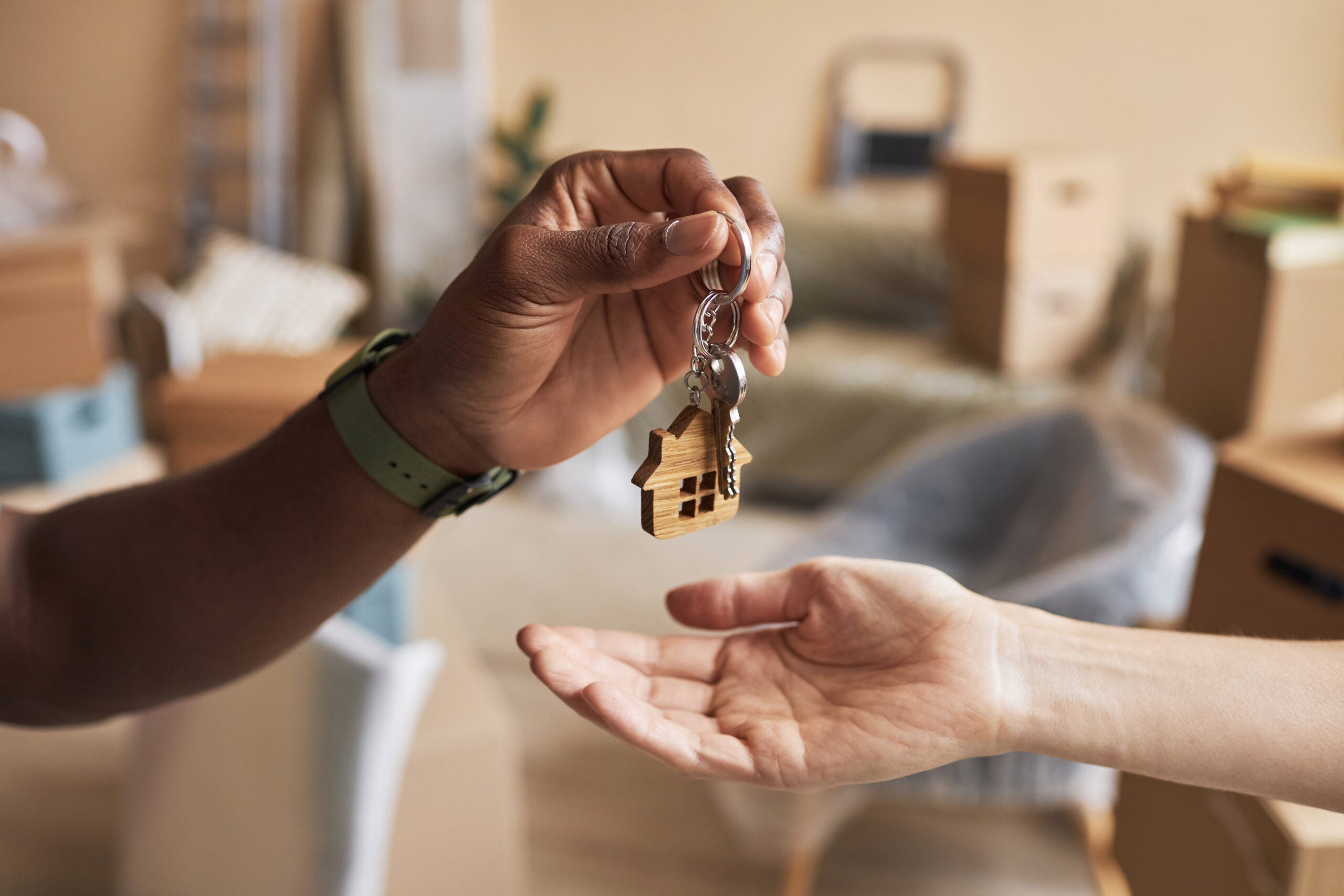 A hand drops house keys into another person's hand