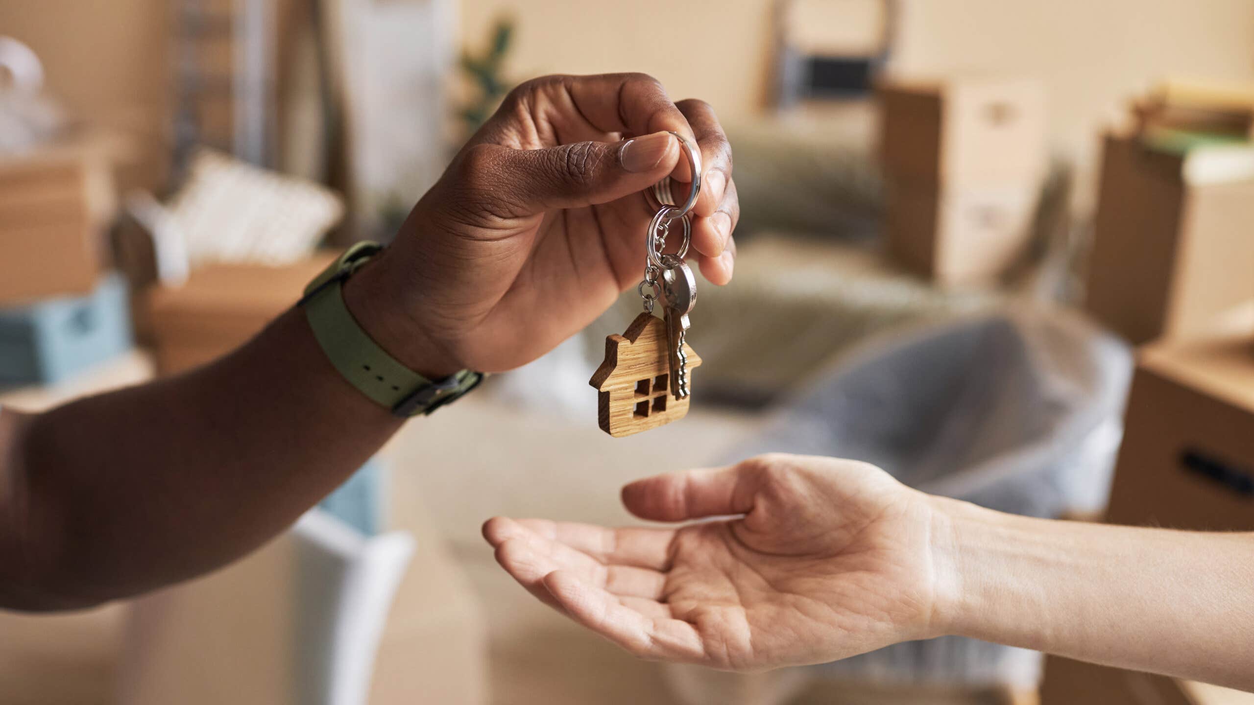A hand drops house keys into another person's hand