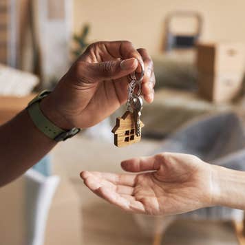 A hand drops house keys into another person's hand