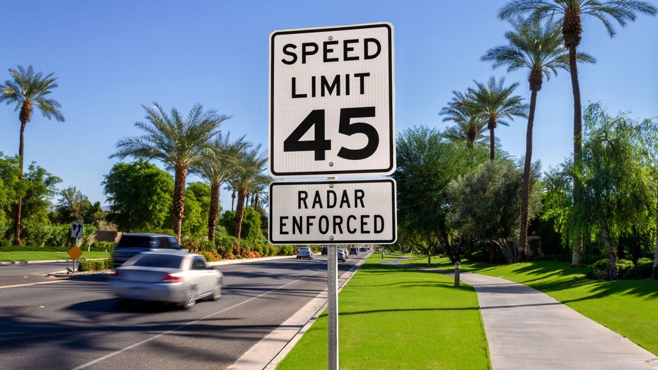cars passing by a speeding limit sign
