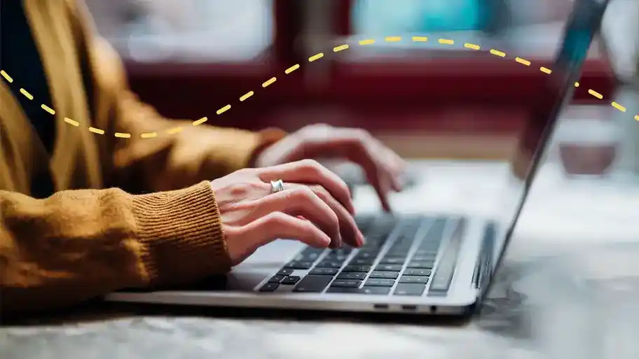 Person using a laptop to work on their desk