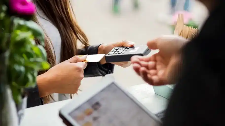 a person inserting a credit card into a hand held card reader